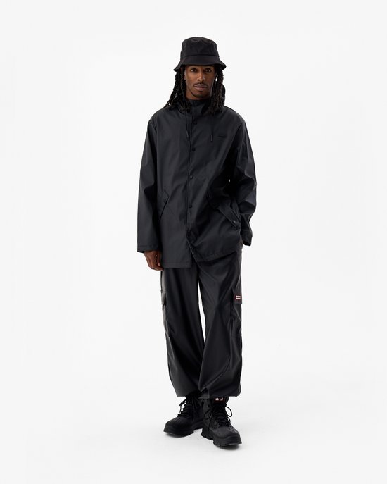 Man met dreadlocks, draagt een zwarte regenjas, cargo broek en vissershoedje. Glanzende stof.