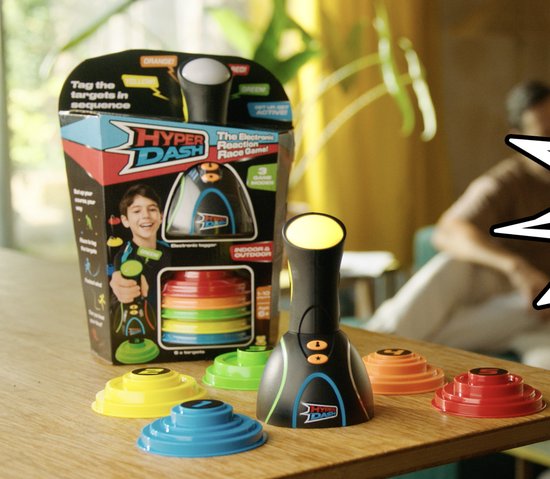 Een Hyper Dash spel inclusief spelconsole en gekleurde targets op een tafel, met verpakking ernaast.