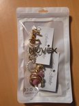 Verpakte set van 10 oorbellen met diverse designs: vlinders, gouden staafjes, parel-look, acryl, schakels, in goudkleurig, roze en wit.