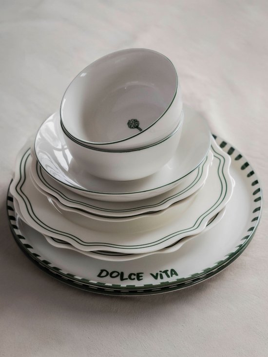 Gestapeld servies: borden, schalen en een kom, met groene randen en 'DOLCE VITA' tekst.