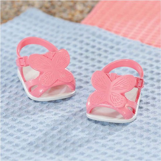 Roze babyschoentjes met vlindermotief, op blauw geruit doek.