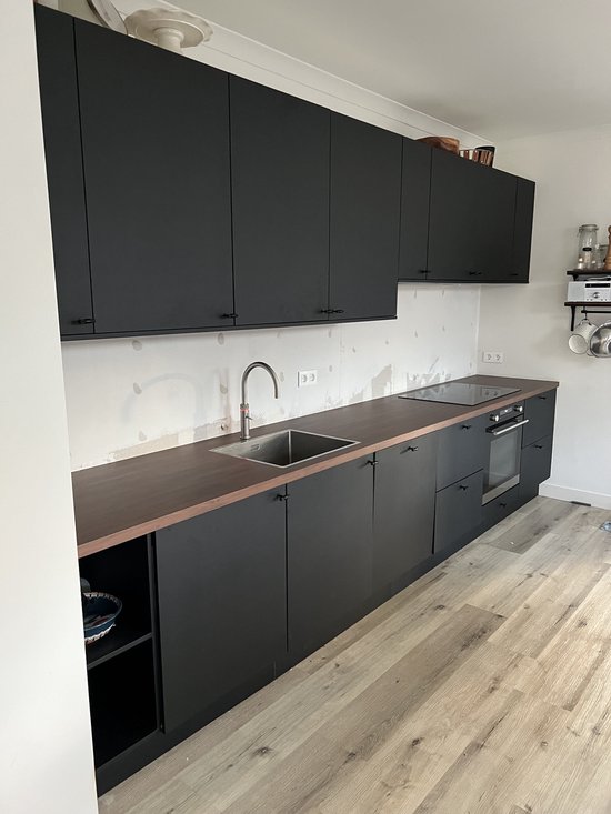 Moderne zwarte keuken met houten accenten en een roestvrijstalen gootsteen.