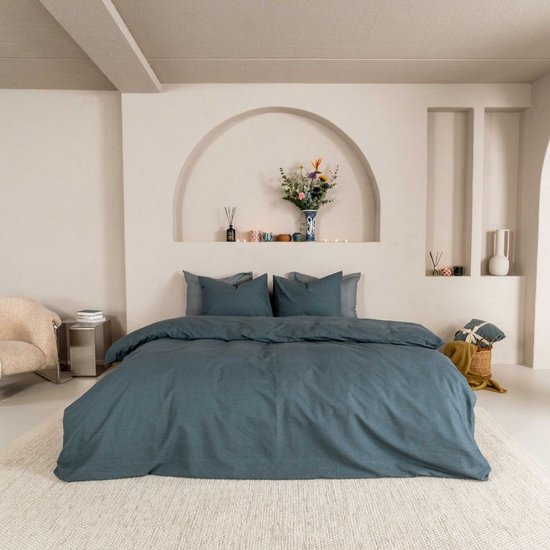 Een compleet opgemaakt bed met donkerblauwe dekbedovertrek en kussenslopen, in een slaapkamer.