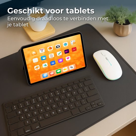 Witte draadloze muis met RGB verlichting naast een tablet met kleurrijk scherm en een zwart toetsenbord.