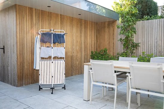 Wit droogrek met opgevouwen gestreepte handdoeken en kleding in een tuin.