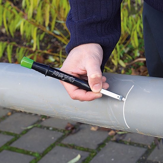 Hand met Pica Big Dry markeerstift op grijs PVC-buis. Groene dop.