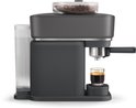 Zwarte Philips Baristina volautomatische espressomachine met een glas espresso.