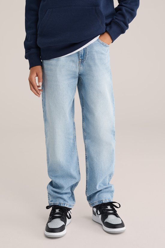 Onderste helft van een jongen die een donkerblauwe hoodie draagt met een lichte spijkerbroek.