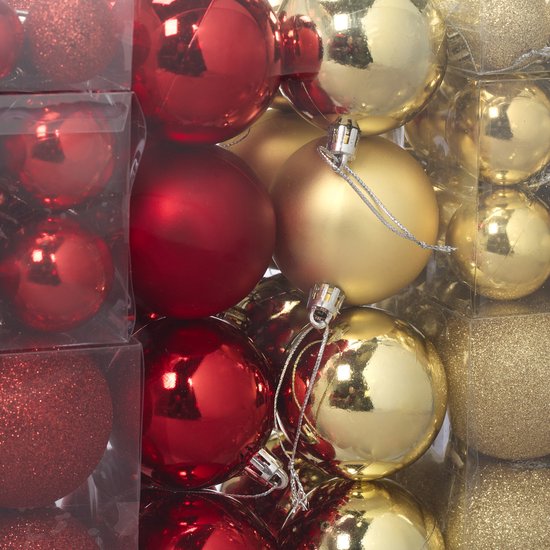 Een close-up van een doos met rode en gouden kerstballen, gladde en glittervarianten.