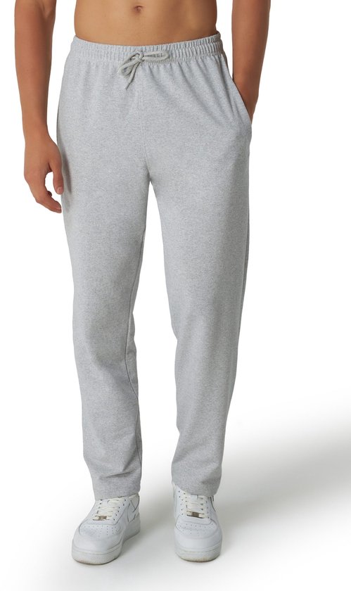 Man van voren, draagt een grijze joggingbroek met trekkoord, rechte pijpen en witte sneakers.