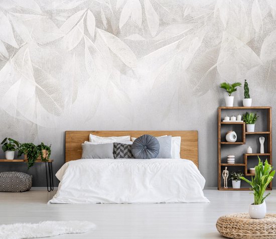 Slaapkamer met een bed, gedecoreerd met een fotobehang van witte veren en bladeren tegen een betonnen muur.