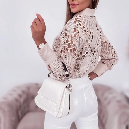 Vrouw met beige kanten blouse, witte broek en witte tas.
