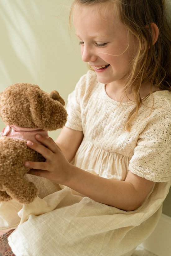 Meisje met bruine knuffelhond met roze bandana.