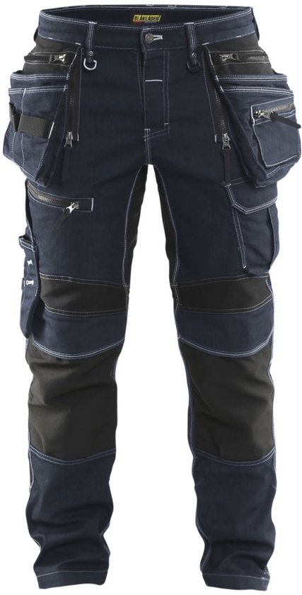 Donkerblauwe spijkerbroek met veel zakken, ritssluitingen en witte stiksels.