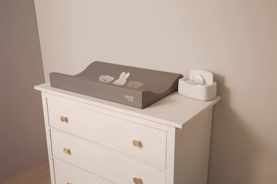 Grijze aankleedkussen met Miffy en vriendjes, op een commode met witte lades en gouden knoppen.