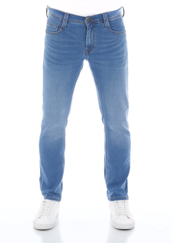 Man van voren in blauwe tapered fit jeans met bruine stiksels en Mustang label.