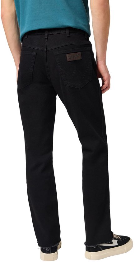 Achterkant van een man in zwarte regular/straight fit jeans en blauwe polo.