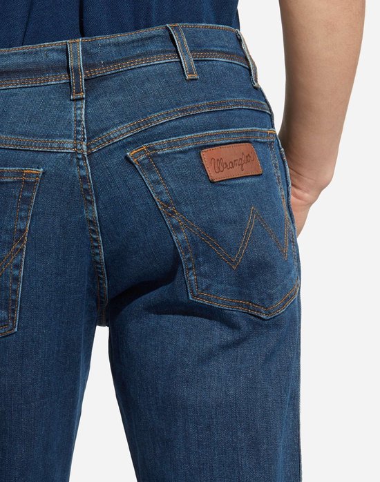 Detail van de achterzak van een blauwe Wrangler jeans met bruin label en Wrangler 'W' stiksels.