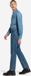 Man, lopend, draagt een blauwe spijkerbroek, denim overhemd en zwarte schoenen, zijaanzicht.