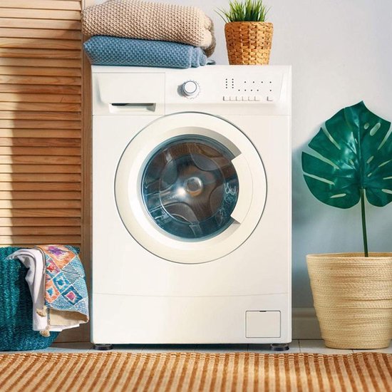 Wasmachine met gestapelde handdoeken en mandjes, staand op zwarte trillingsdempers.