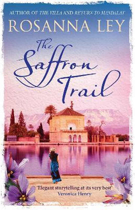 Livre "The Saffron Trail" de Rosanna Ley avec une illustration d'un bâtiment au bord d'un lac avec des fleurs violettes au premier plan.