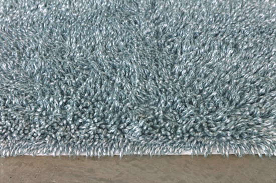 Detail van een zachte, lichtgroene badmat met een pluizige textuur en witte rand.