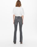 Achterkant van het model in grijze flared jeans met witte T-shirt.