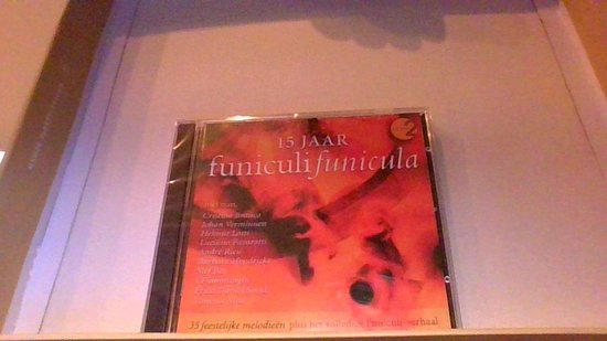 CD-hoes met tekst '15 JAAR funiculi funicula' en lijst met artiesten, rode en oranje abstracte achtergrond.