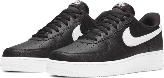 Paar zwarte leren Nike Air Force 1 sneakers met witte zolen en logo's, van voren gezien.
