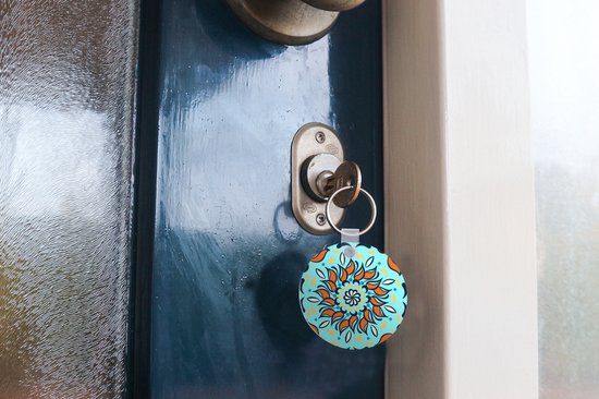 Porte-clés - motif sur fond bleu clair avec une fleur orange et des décorations - Plastique - Rond