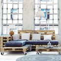 Woonkamer met een bank en salontafel gemaakt van houten pallets, met zwenkwielen eronder.