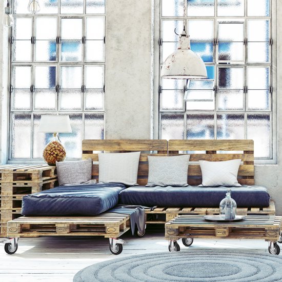 Woonkamer met een bank en salontafel gemaakt van houten pallets, met zwenkwielen eronder.