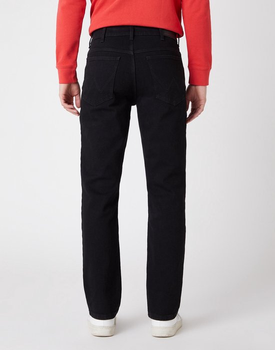 Achterkant van een man in een zwarte jeans met rode trui. Rechte pijpen, vijf zakken.