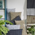 Stapel kussens met bolletjespatroon in grijs en beige. Gebreide stoffen op een ladder.