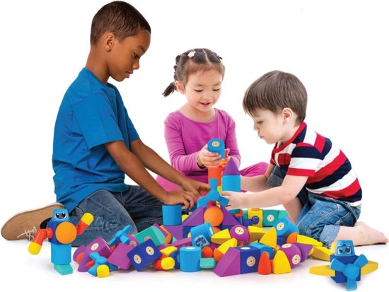 Drie kinderen spelen samen met felgekleurde magnetische bouwblokken, zittend op de grond.