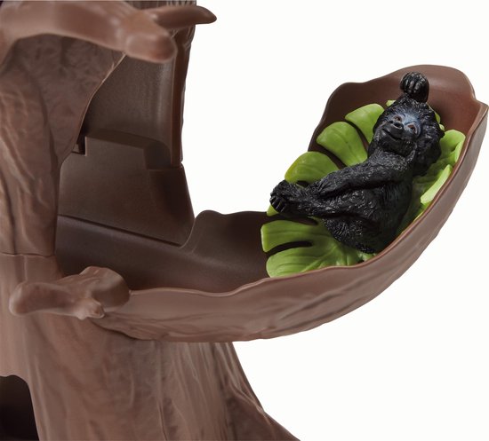 Speelgoed baby gorilla die slaapt in een bruine schommel in een boom.