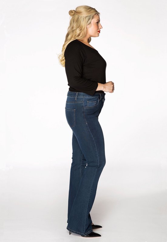 Vrouw met blond haar, zijaanzicht, draagt een zwarte top en een donkerblauwe flare jeans.