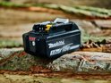 Zwarte Makita 18V 5.0Ah Li-ion accu met rode batterij-indicator, op houten achtergrond.
