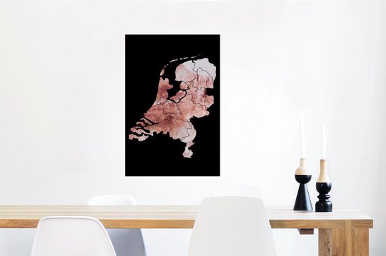 Affiche des Pays-Bas en teintes rose délavé avec bordure noire, suspendue à un mur blanc au-dessus d'une table en bois.