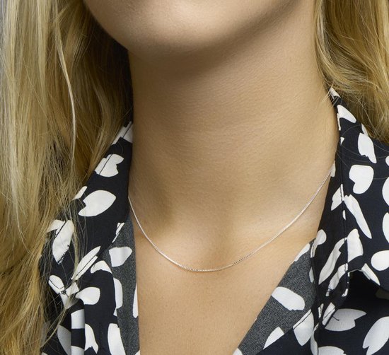 Een zilverkleurige, fijne venetiaanse schakelketting met een lengte van 42 cm om de nek van een model.