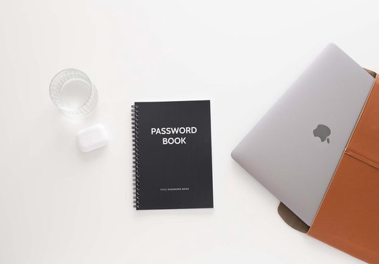 Zwart 'PASSWORD BOOK' notitieboek naast een laptop, glas water en oortjes.