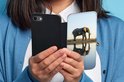 Een vrouw houdt een zwarte portemonnee telefoonhoes open. De print toont een olifant bij een waterplas.