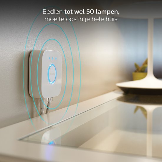 Philips Hue Bridge hangt aan de muur, met blauwe cirkels die de verbinding met lampen suggereren.