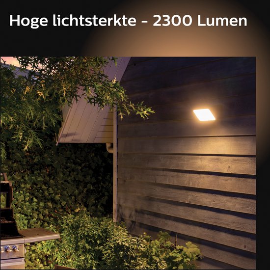 Een buitenlamp met 2300 lumen schijnt op een houten schuur en tuin in de avond.