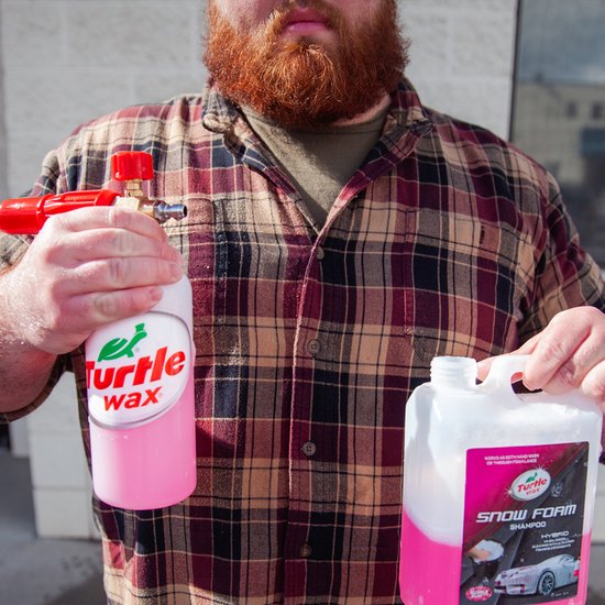 Turtle Wax Snow Foam Shampoo fles met rode spuitkop en een jerrycan met roze vloeistof.