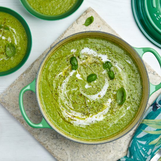 Groene soep in een groene braadpan, gegarneerd met basilicum.