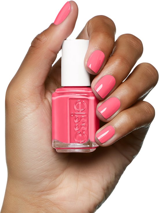 Een hand met gemiddelde huidtint houdt Essie nagellak 'cute as a button' vast, met bijpassende nagels.