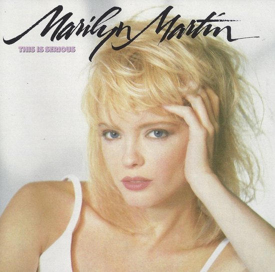 Een blonde vrouw met een witte top, met de hand in haar haar. Tekst: Marilyn Martin THIS IS SERIOUS.