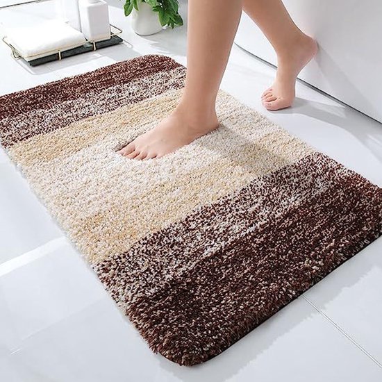 Een zachte, gestreepte badmat met bruine, beige en witte banen, waarop blote voeten staan.