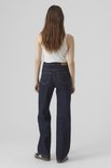 Model van achteren in donkerblauwe wijde jeans, witte top en sneakers.